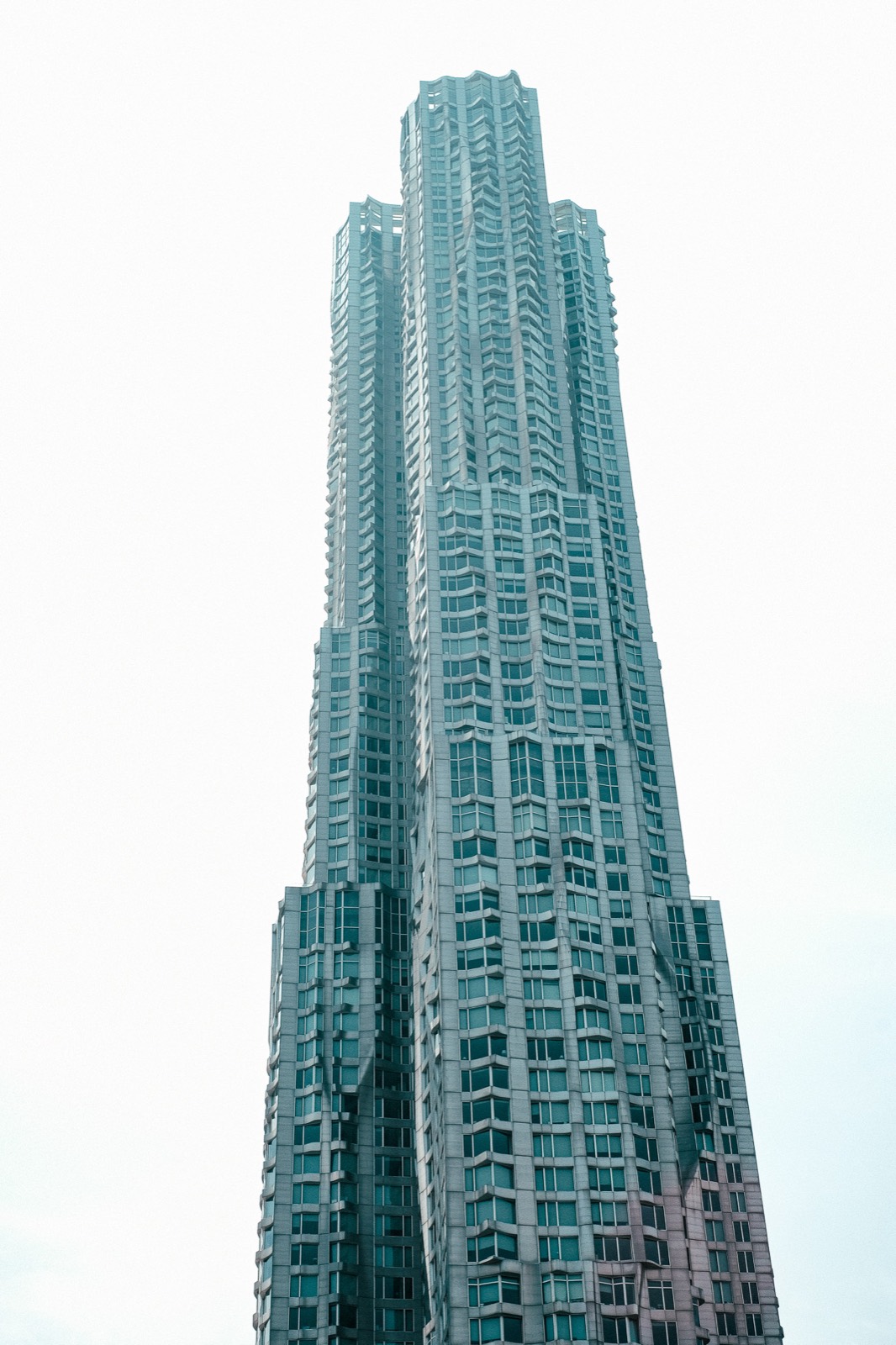 A rippling glass residential tower rising against a washed white sky in New York.